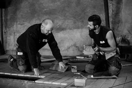 Deux artisans Macoretz travaillent sur la pose d'un carrelage