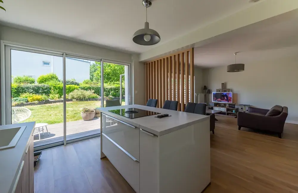renovation-interieure-maison-vue-cuisine-baie-vitree-3-vantaux-donnant-sur-jardin-claustra-bois-separation-piece-de-vie-saint-herblain